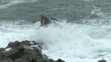 Bir kayalık yakınındaki Cape Elizabeth, Maine Portland Head ışıkta çıkıntının üzerinde çökmesini dalgalar.