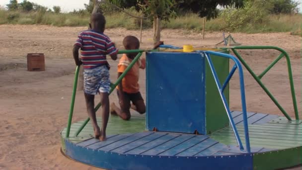 アフリカでのメリーゴーラウンドで遊ぶ二人の少年のワイド ショット — ストック動画