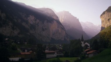 Lauterbrunnen, İsviçre'nin şafakvakti statik fotoğrafı. Şehir ve tarihi şehir kiliseye doğru kayalık kayalıklar üzerinde güneş ışığı ışınları.
