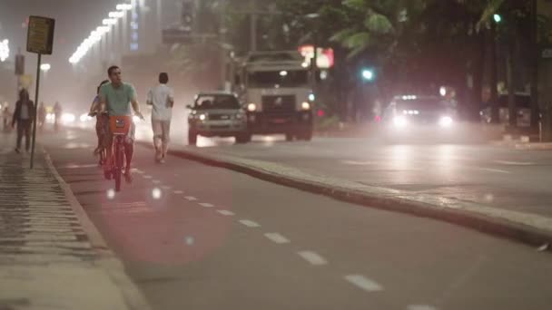 里约热内卢 2013年6月 自行车道与自行车手和跑步者射击 车道由中位数分隔 中位数的另一边是交通所在的位置 交通繁忙 车辆在开灯时通过并行驶 — 图库视频影像