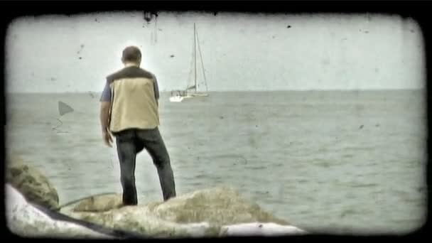釣り人のショット 彼はヨットが経つにつれてイタリアで岩に立っています ビンテージの様式化されたビデオ クリップ — ストック動画