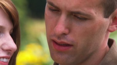 Genç bir adam güzel bir bahçe içinde genç bir kadın için öneriyor.