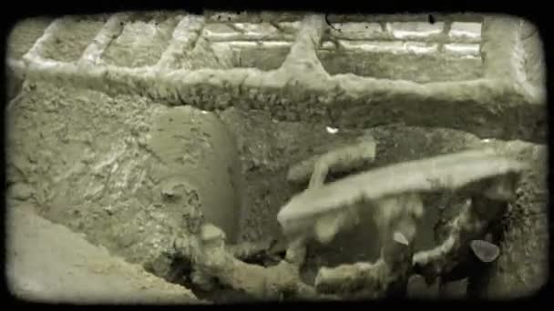大型砂浆水泥机在建筑工地用凌乱的水泥覆盖的箱子下面搅动泥土 岩石和水泥 因为工人将更多的泥土铲入混合物中 复古风格化视频剪辑 — 图库视频影像