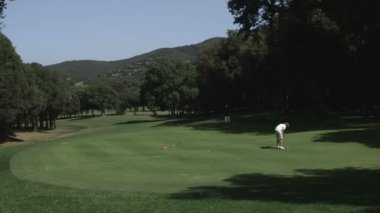 Adam uzun bir putt golf üzerinde yeşil yapma.