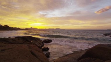 Gün batımında kıyı kayalarını yıkanan gelgit. Ipanema plajında çekildi, Rio de Janeiro, Brezilya.