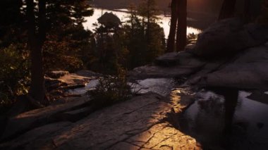 Ağaçlarla çevrili derenin alacakaranlık çekimi. Nehir arka planda görülebilir. Güneş ışığı arka planda da görülebilir. Emerald Bay State Park, Lake Tahoe, Kaliforniya'da vuruldu.