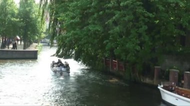 Amsterdam, Hollanda - 2012 yaklaşık: Atış bir teknenin Hollanda'nın Amsterdam, ağaç dalları altında bir kanal aşağı.