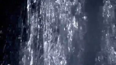 Karanlıkta kalan su bir parlak, arkadan aydınlatmalı çağlayan bir close-up.