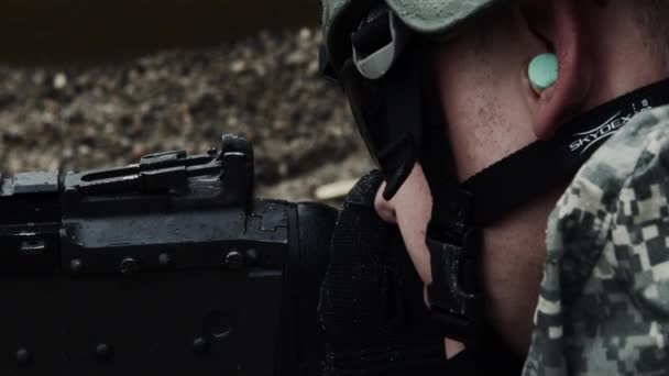 士兵瞄准皮带机枪并开火的特写镜头 他戴着耳塞和头盔 从绿色贝雷雷美国陆军特种部队的训练 — 图库视频影像