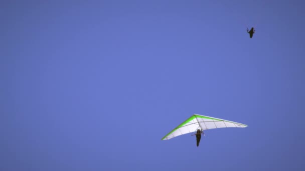 镜头是一个孤独的悬挂滑翔机 很快加入了滑翔伞 悬挂式滑翔机移出视线 在镜头中单独留下滑翔伞 — 图库视频影像