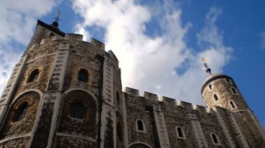 Aşağılardan atış mavi gökyüzü ve zaman atlamalı bulutların üzerinde kule ile uzun boylu, taştan Londra Kulesi
