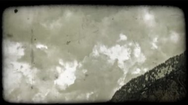 Kabarık bulutlar yavaş yavaş tarafından karla kaplı dağ üst kenarını kış ağaç ön planda ipuçları ile birlikte kayması. Vintage stilize video klip.