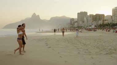 Rio De Janeiro-Haziran16, 2013: Diğerleri suda dururken plaj da yürüyen bir çift yavaş çekim izleme çekim. Rio de Janeiro, Brezilya'da çekildi.