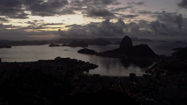 夕暮れ時の高い眺めからブラジル リオデジャネイロ市の静止したショット 都市と湾は シャでフレームの下半分を埋め 空と山は上半分を構成します 街の明かりが見える — ストック動画