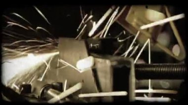 Adam kesme metal ön planda büyük kanatlı makine ile adam arka planda koruyucu fabrika kıyafetleri giymiş ve ambar kaynak bir tüp ile kaynak olarak kask üzerinde metal işleri virajlı yakın çekim.