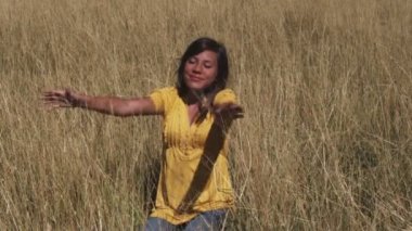 Meditatif bir biçimde kollarını hareket ederken rahat bir pozisyonda gülümseyen kadın oturur