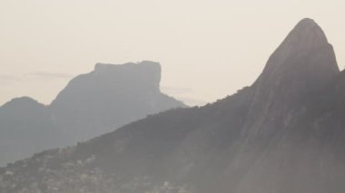 Dois Irmaos dağlarının, Vidigal favelasının ve Rio de Janeiro evlerinin bulutlu bir gökyüzünün ortasında ki çekimlerinin takibi.