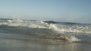 Atlantik sörf kamera içine çeken atış statik. Dalga kum üzerinde bültenleri, karşıt bir akımı zorluklar ve kamera objektifi tüketir. Bir mavna uzaktan görülür.