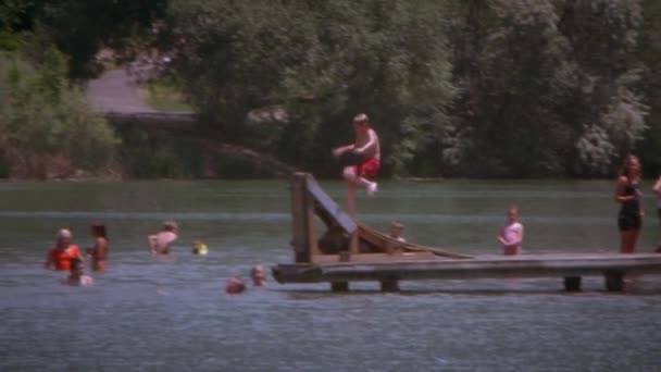 少年はランプをオフを実行している水の中に反転のスローモーション撮影 彼はドックの端に水 Ffrom 反転と カメラは彼を次します — ストック動画
