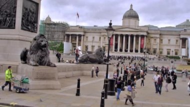 Londra, İngiltere - Ekim 11, 2011: Trafalgar Meydanı'nda Pirinç aslan heykelleri yakınında kimliği belirsiz insanların yavaş hareket sabit görünümü, arabalar Londra İngiltere'de ön planda kamera geçmek.
