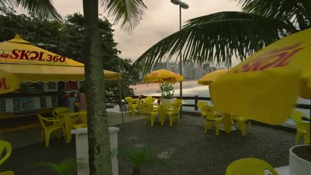 ジャネイロ ブラジル 2013 スローモーション ドリー ショット ブラジル ジャネイロのコパカバーナの屋外カフェ 黄色のテーブルと椅子をカバーする黄色のパラソル プライア — ストック動画