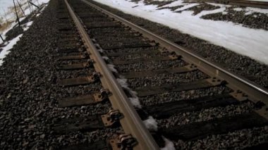 Tren rayları ve dağ kayalıklarının eğimli yakınlaştırma çekimi. Kışın çekilmiş.