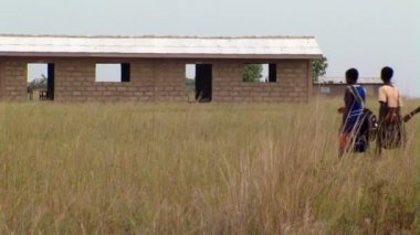 Afrika, Kenya - Ağustos 2010 yaklaşık: Geniş alan ile shcoolhouse arka planda yürürken çocuk vurdu.