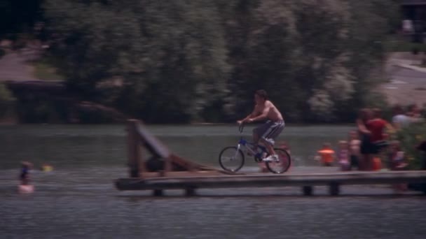 Movimento Lento Tiro Panning Garoto Pulando Sua Bicicleta Girando Lago — Vídeo de Stock