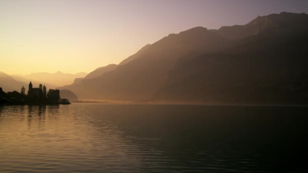 夜明けに穏やかなブリエンツ湖に対してシルエットブリエンツ教会の静的なショット — ストック動画