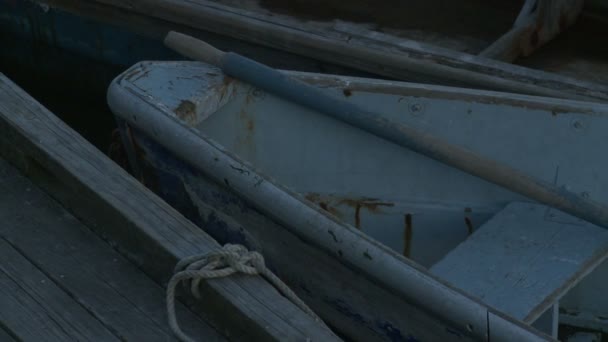 つの古い 木製手漕ぎボート 剥離ペイントでのクローズ アップ ショット ドックにオフ縛らと波と潮の流れを優しくロッキングです マサチューセッツ州ロックポート — ストック動画