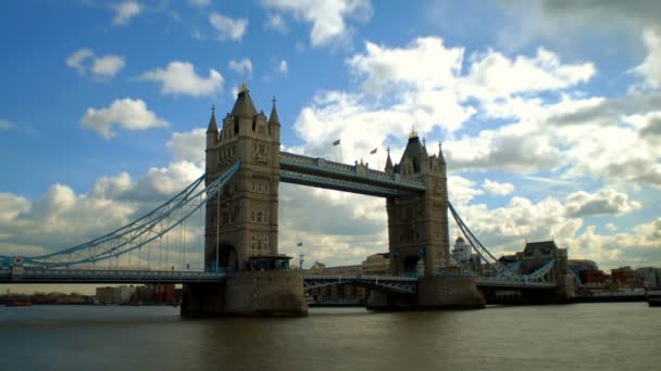 ロンドン イングランド テムズ川の水だけでなく すべての空の上で時間の経過に沿って移動する迅速なふわふわの雲の下で運河の反対側の建物に隣接し 橋のほとんどを示す有名な歴史的なタワー ブリッジの完全なビュー — ストック動画