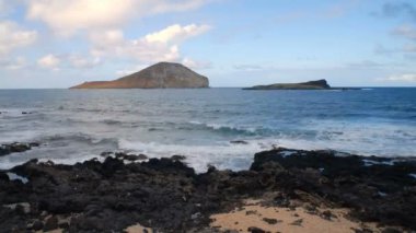 Hawaii Sahili Tavşan Adası ile ön plan ve yumuşak bulutlar yükü timelapse hareket tarafından sürüklenen kum ve lav taşın kırma dalgalar okyanusta güzel manzara.