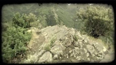 Pan, sağdan sola yaz dağ manzaralı yemyeşil, yeşil Kanyon dağlar ve vadiler yanındaki kayalık çıkıntıya, ağaçlar ve fırça parlak bulutlu gökyüzü yukarıdaki ile kaplı. Vintage stilize video klip.