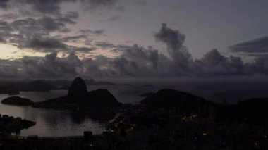 Sağdan sola Rio de Janeiro şehrine arasında Brezilya tava bir atış. Bu alacakaranlıkta ve şehrin ışıkları görülebilir. Şehir ve bay tabandan çerçevenin yarısını ve gökyüzü ve dağlar yarım kalan doldurun.