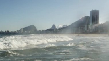 Atlantik Okyanusu içine bir plaj Rio de Janeiro çökmesini dalgaları. Okyanus gelgit ücretleri sahile insanlar Sahilde yürüyüş yaparken.