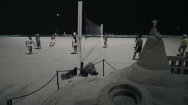 Voleybolcular kaydırma, yavaş hareket mermi Copacabana Plajı kum sanat. Geceleri sahilde filme. 22 Haziran 2013 tarihinde gece filme.