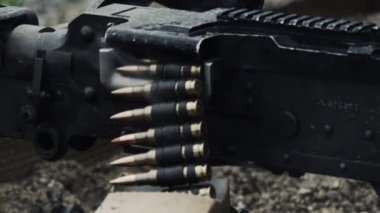 Kemerle beslenen bir makineli tüfek ateşlenirken vuruldu. Mermi zincirinin silahtan geçtiği yerin yakın çekimyeri. Ateş edilirken silahtan duman çıkıyor. Yeşil Bereli Abd Ordusu Özel Kuvvetler için bir eğitim gönderen.