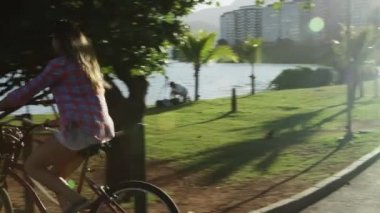 Rio de Janeiro - 18 Haziran 2013: izleme, sürme iki kadın ağır çekim görüntüleri kaydırma motosiklet kameraya doğru ve sonra uzak bir küçük iskele Rio de Janeiro'nun Lagoa uzanan üzerine binmek için açmak gibi.