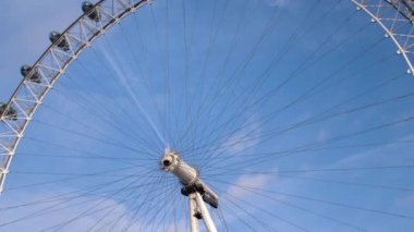 London Eye Londra, İngiltere'de arka planda mavi bulutlu gökyüzü ile düşük açılı görünümü.