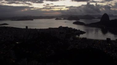 Soldan sağa doğru Rio de Janeiro şehrine arasında Brezilya tava bir atış. Bu alacakaranlıkta ve şehrin ışıkları görülebilir. Şehir ve bay tabandan çerçevenin yarısını ve gökyüzü ve dağlar yarım kalan doldurun.