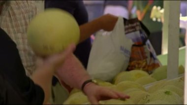 Bir açık hava pazar tezgahında duran ve kavunları inceleyen bir dizi insan. Filmedin Salt Lake City, Utah.
