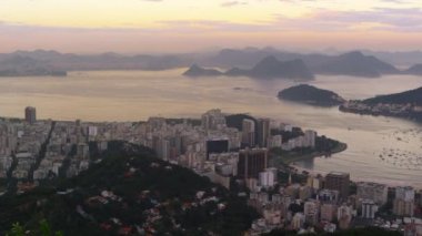 Şehir ve Rio de Janeiro şehrine deniz üzerinde güzel bir pembe ve mavi gün batımı yavaş bir pan yakalar