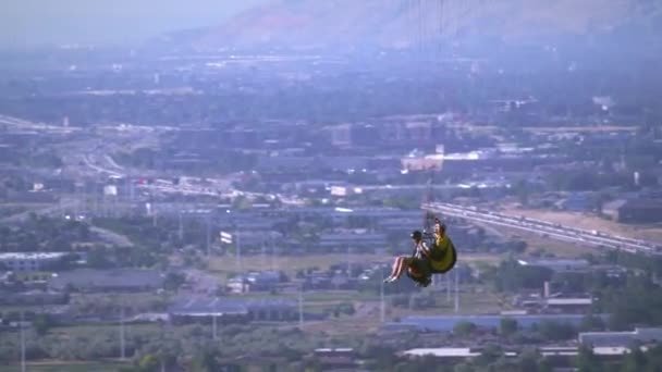 两个人在一起 滑翔伞一别人一个降落伞 他们通过另一个滑翔伞 在下面可以看到山谷和公路 — 图库视频影像