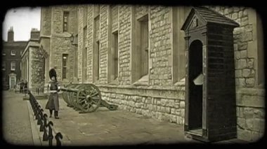 Genç korumak, resmi üniforma ve uzun boylu şapka giymiş, tüfek taşıyan ve toplar ve istinat duvarı tarihsel tuğla Londra, İngiltere'de bina dışında yakın yürüyüşleri. Vintage stilize video klip.