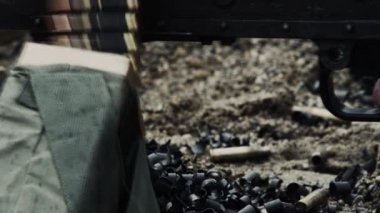 Kemerle beslenen bir makineli tüfek ateşlenirken vuruldu. Atılan kovan ve kemer parçaları yığınına hareket eden mermi zincirinin yakın çekim. Ateş edilirken silahtan duman çıkıyor. Yeşil Bereli Abd Ordusu Özel Kuvvetler için bir eğitim gönderen.