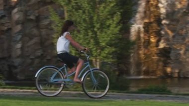 Ağır çekim shot genç bir kadının güzel bir bahçe ile bisiklet sürme.