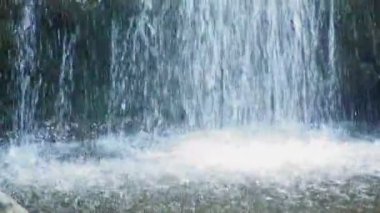 Closeup şelale olarak su altındaki kayalık zemin karşı bir gölet yüzeyinin hits.