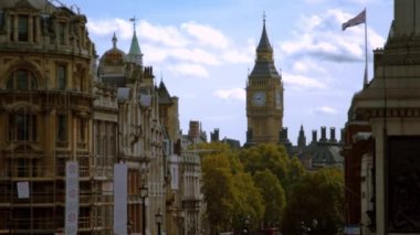 Big Ben Saat Kulesi, sabit bir kadeh Trafalgar Meydanı'na yakın Lord Nelson'ın anıt filme. Binalar, İngiliz bayrağı, ağaçlar, bulutlu gökyüzü ve de gördüm geçen kuş sallayarak.