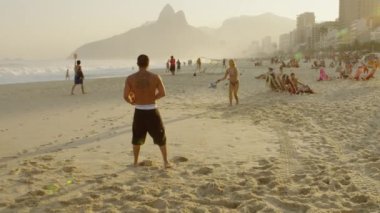 Rio De Janeiro, Brezilya - 24 Haziran 2013: Dolly itme yürür bir kadın kamera geçmiş ve çerçeve, gelen ışık içinde bir mercek parlaması bakıyor gibi tenis Ipanema Plajı üzerinde güneşin birlikte oynamak bir çift dışarı
