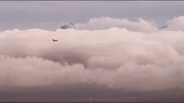 看起来小的飞机飞过云海在盐湖城 犹他州 一座山峰是勉强可见的云层上方 — 图库视频影像